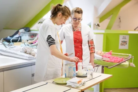 Une jeune en formation qui apprend à préparer et donner les biberons aux bébés avec sa professeur