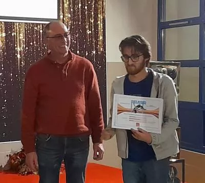 élève qui pose avec son diplôme avec son enseignant à coté.
